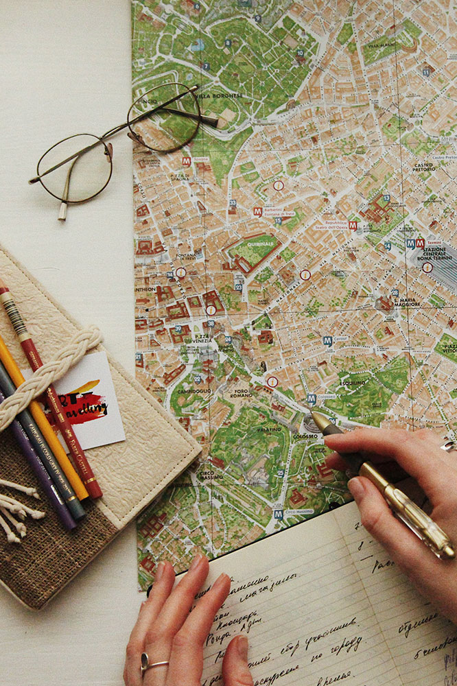 Person writing in a notebook with a map on the desk