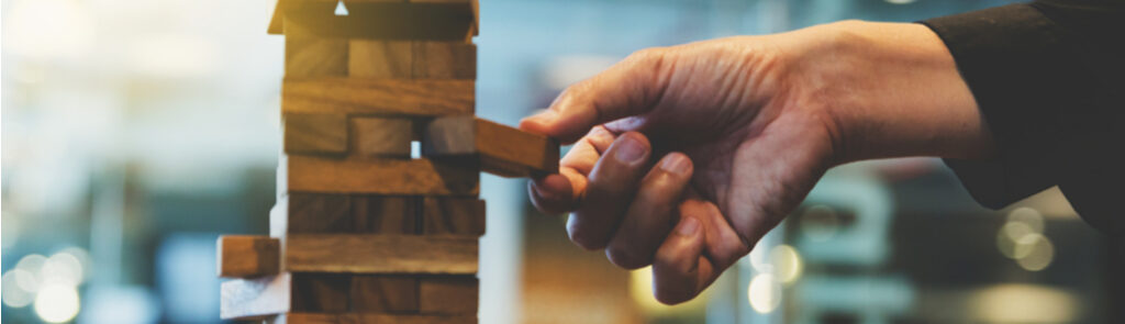Hand removing a wooden block from a Jenga game