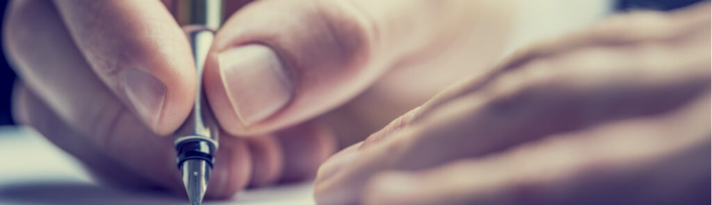Close up of a hand holding a pen to paper