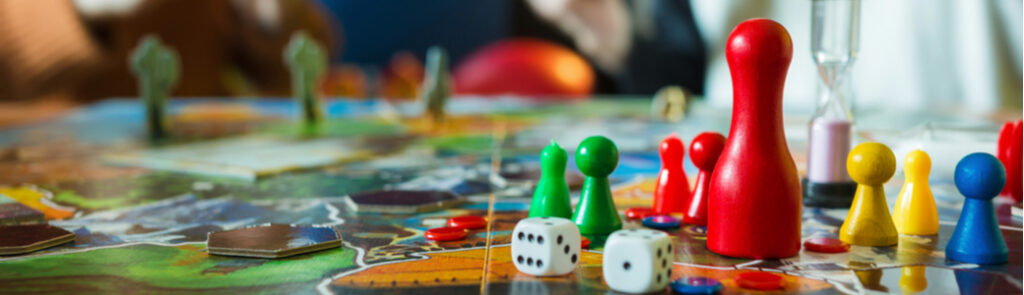 Close up of board game pieces and people playing in the background