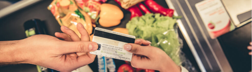 A customer handing over a bank card to pay for goods in a supermarket.