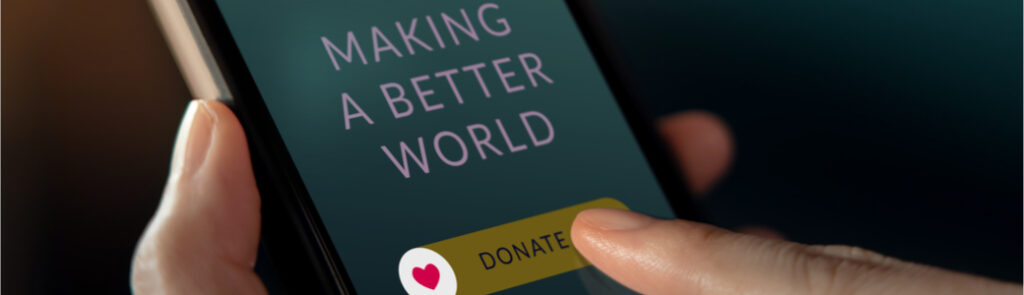 Someone holding a phone and pressing a “donate” button on the screen.