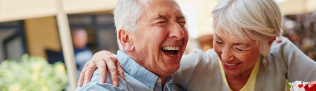 A retired couple laughing at a café.