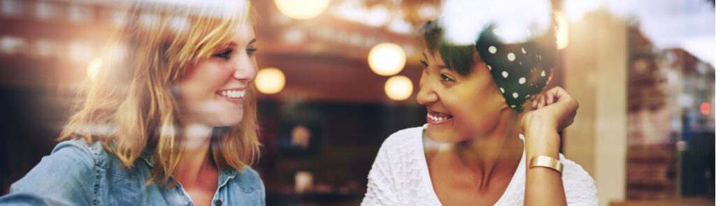 Two women talking while drinking coffee.