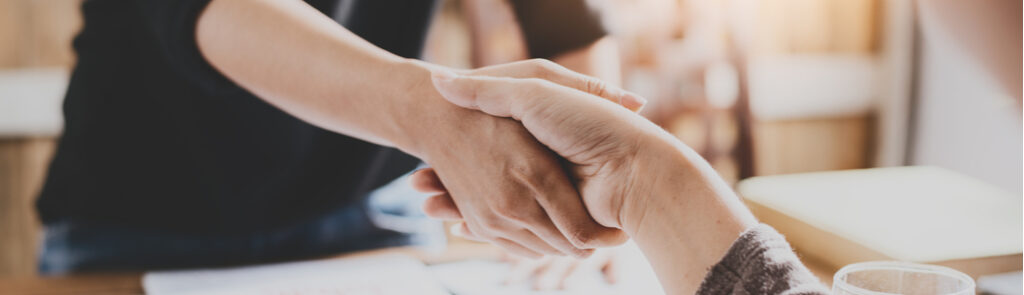 Two people shaking hands in an office.