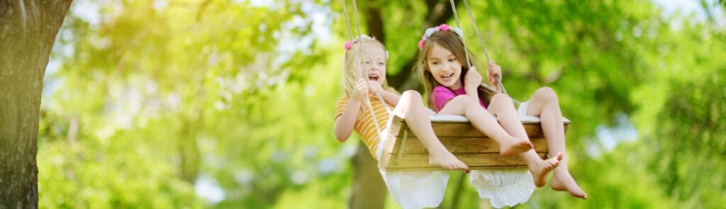 Two girls playing on a swing.