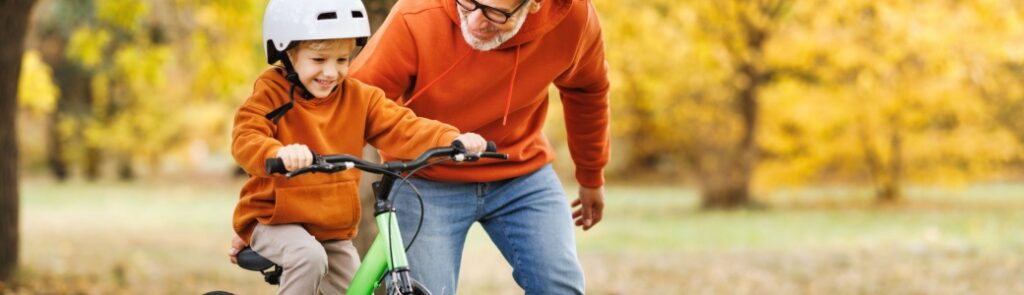 A man teaching his grandson to ride a bike.