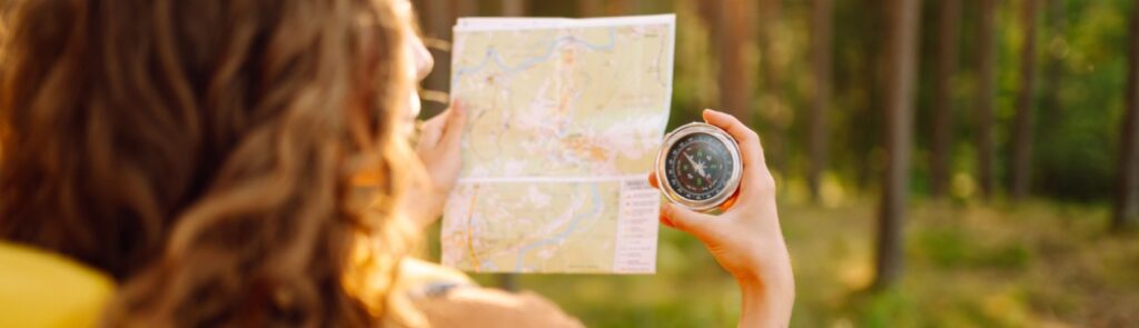 A young woman hiking and using a compass.