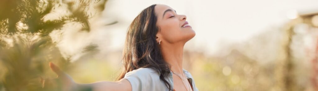 A woman outdoors with her arms outstretched.