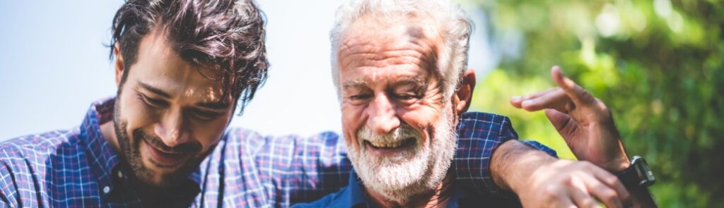 A father walking outdoors with his adult son.