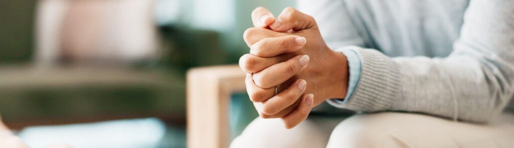 A woman sitting with her hands clasped.
