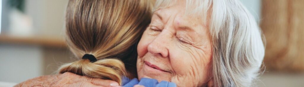 A senior woman hugging a caregiver.