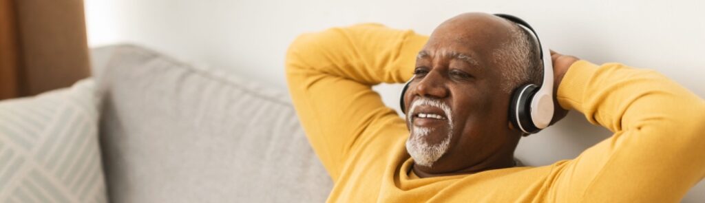 A man relaxing on a sofa with his hands behind his head.