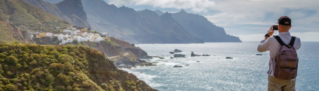 A male traveller taking a photo of a scenic coast.