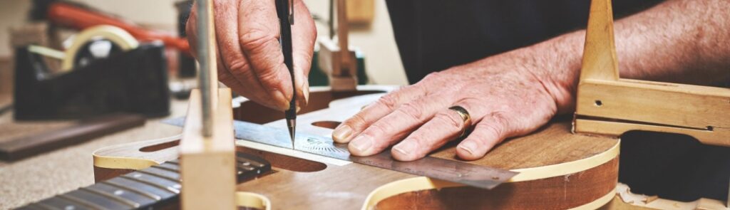 A man fixing a guitar in a workshop.