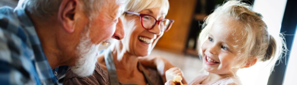 Happy smiling grandparents enjoying time with grandchild at home