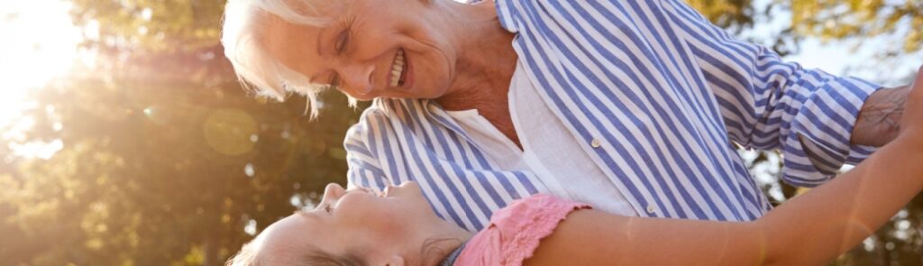 A grandmother playing with her granddaughter outside.