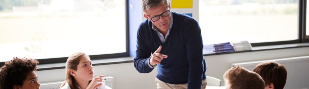 A teacher talking to a group of pupils in a classroom.