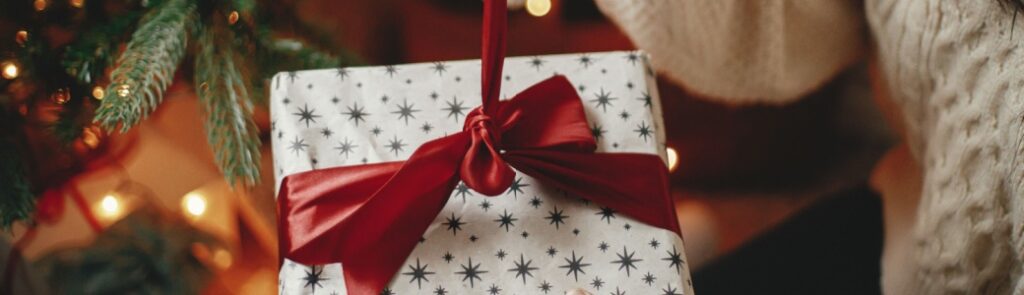 A woman untying a ribbon on a Christmas present.