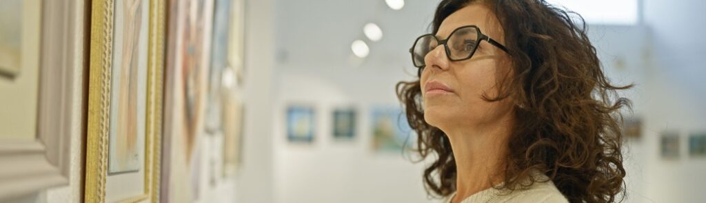 A woman looking at a painting in an art gallery.