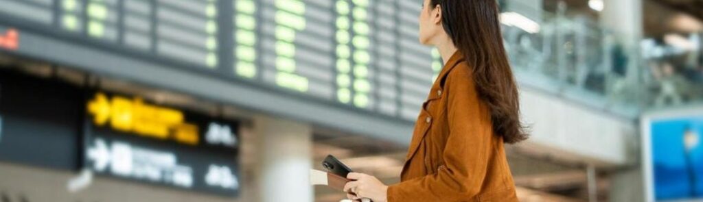 A woman looking at a departure board in an airport.
